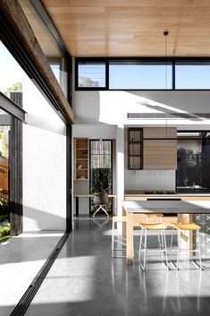 an open kitchen and dining area with wood ceilinging, glass walls, and floor to ceiling windows