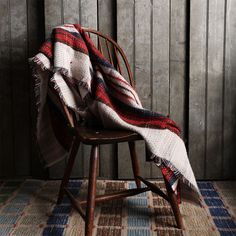 a chair with a blanket on top of it in front of a wooden paneled wall