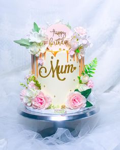 a birthday cake decorated with flowers and leaves on a silver platter that says happy birthday mum