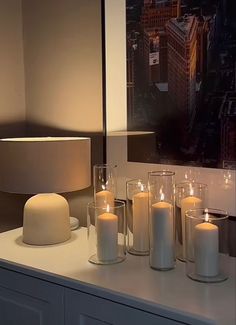 there are many lit candles on the counter in front of a large photograph with city lights behind it