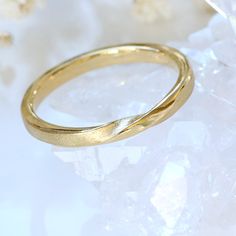 An elegant plain band ring featuring a single twist in the centre. Representing the infinite union of two sides, this stylish ring is ideal as a wedding band or friendship ring. Handmade using recycled 18ct gold, each ring is made to order using traditional jewellery making methods. The 2mm band is solid gold with a flat profile and Lilia's Spun Silk finish with polished edges. Available in any UK ring size including half sizes. Customise the design by adding diamonds or other details with Lilia Elegant Gold Bands From Recycled Gold, Elegant Recycled Gold Bands, Elegant Yellow Gold Bands With Recycled Gold, Simple Gold Wedding Band 3mm, Twist Wedding Ring, Minimalist Recycled Gold Yellow Bands, Ring Chart, Single Twist, Birthstone Stacking Rings