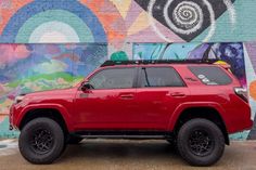 a red truck parked in front of a colorful wall