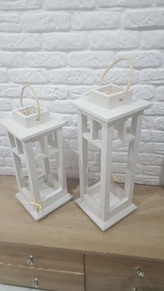 two white lanterns sitting on top of a wooden table