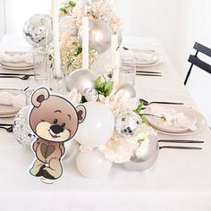 there is a table set with white and silver decorations for a baby's first birthday