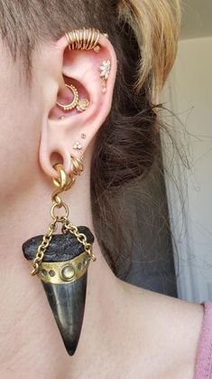 a close up of a person with ear piercings and an ear chain attached to their ears