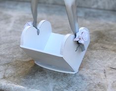 an origami heart shaped box with scissors sticking out of the top, sitting on a marble surface