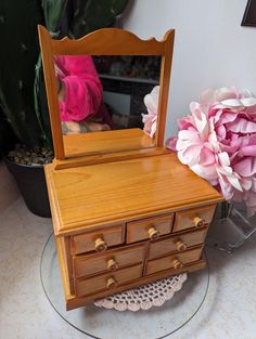 a wooden dresser sitting next to a pink flower