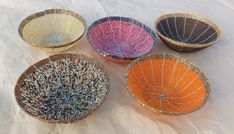 four woven baskets sitting on top of a white sheet