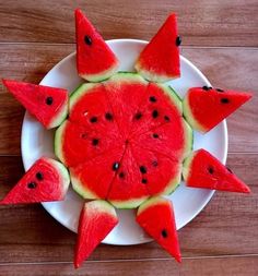 slices of watermelon arranged in the shape of spikes on a white plate with wood flooring