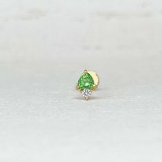 a green and white diamond ring sitting on top of a table