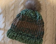 a knitted hat with a pom - pom sitting on top of it