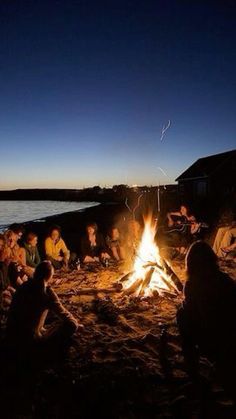 a group of people sitting around a campfire at night