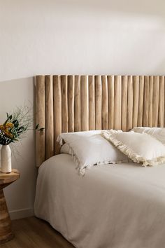 a bed with white sheets and pillows in a room