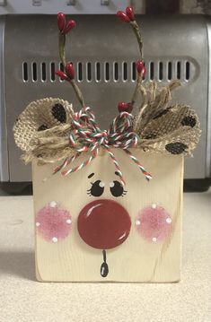 a wooden block with a reindeer head on it's face and candy canes sticking out of the nose