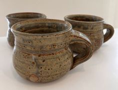 three coffee mugs sitting next to each other on a table