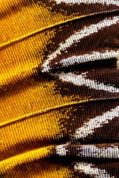 close up view of the pattern on an african cloth with yellow, brown and white colors