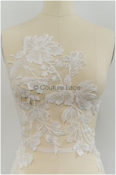 the back of a wedding dress with white flowers on it, and lace trimming