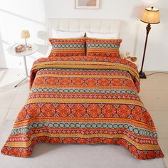 a bed with an orange bedspread and matching pillow cases in a white room