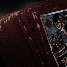 a close up of playing cards on a dark surface with the number 3 in front of them