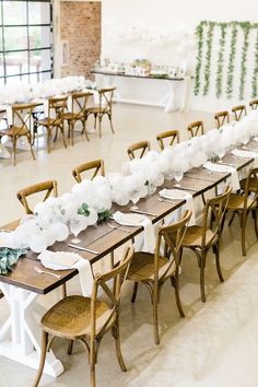 a long table set up with white flowers and greenery on the tables for an event