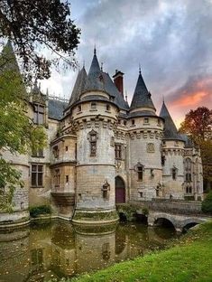 an old castle sitting next to a body of water in front of a sunset sky