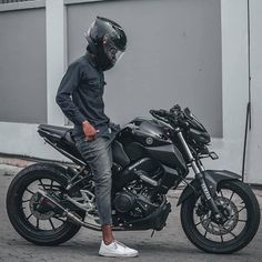 a man sitting on top of a black motorcycle wearing a helmet and grey sweatpants