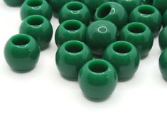 green ceramic beads are lined up on a white surface