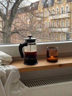 a coffee pot sitting on top of a window sill next to a jar of liquid