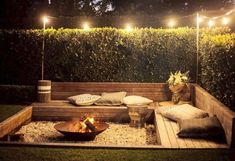 a wooden bench with pillows and lights on it in the middle of a yard area