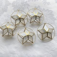 four small glass dishes sitting on top of a white tablecloth covered table next to a lace doily