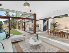 a living room filled with furniture next to a large glass wall covered in greenery