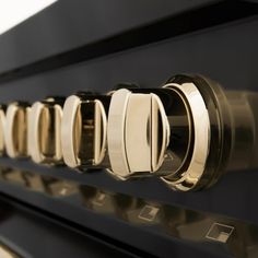 the knobs on an oven door are shiny gold and black, with white trim