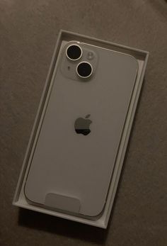 an apple phone in its box on the table with it's camera lens open