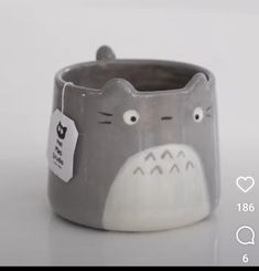 a gray and white cat mug with a tag on it