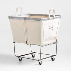 a white shopping cart with two canvas bags on the front and one is attached to it