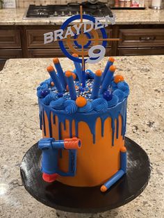 a birthday cake with blue icing and orange drips on it, sitting on a kitchen counter