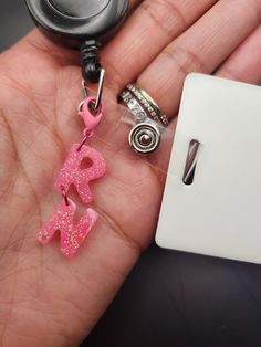 a hand holding a pink keychain with the word love spelled out in small letters