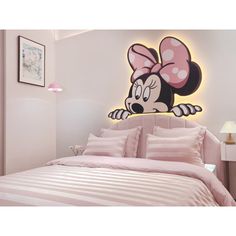 a bed room with a neatly made bed and a minnie mouse wall decal