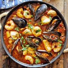 a pan filled with seafood and mussels on top of a wooden table