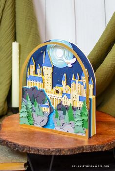 a card with a castle in the background on a wooden table next to a candle