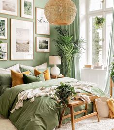 a bedroom with green walls and pictures hanging on the wall above the bed, along with a wicker basket