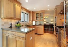 a large kitchen with wooden cabinets and stainless steel appliances, along with hardwood flooring