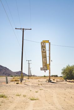 a motel sign in the middle of an empty desert area with telephone poles and power lines