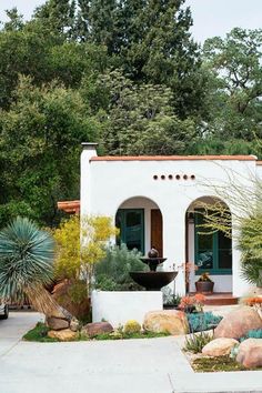 a white house with plants and rocks in the front yard