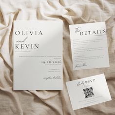 the wedding stationery is laid out on top of the bed sheet, which has been folded in two separate sections