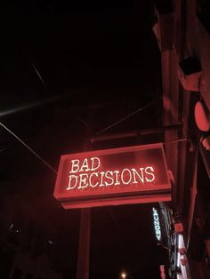 a red neon sign that says bad decision on the side of a building at night