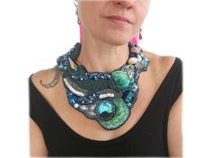 Statement necklace with dolphin Opulent statement chain for special occasions.Beads, shells, silk and crystal were elaborately crafted by hand.Get this handmade unique piece now!Measures: close-fitting, fits up to a neck circumference of 15,74"Material: Alcantara imitation fabric, rocailles, resin, metal, shells, shibori silk, extension chainNo tax statement according to German small business regulation §19 Turnover Tax Act.Deliveries outside Germany may be subject to customs and import sales ta