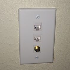 the light switch is white and has two lights on each side with gold trimmings