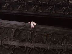 a person's hand on the edge of a wooden bench with intricate carvings around it