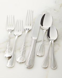 five silverware pieces with ornate designs and spoons on a marble countertop top